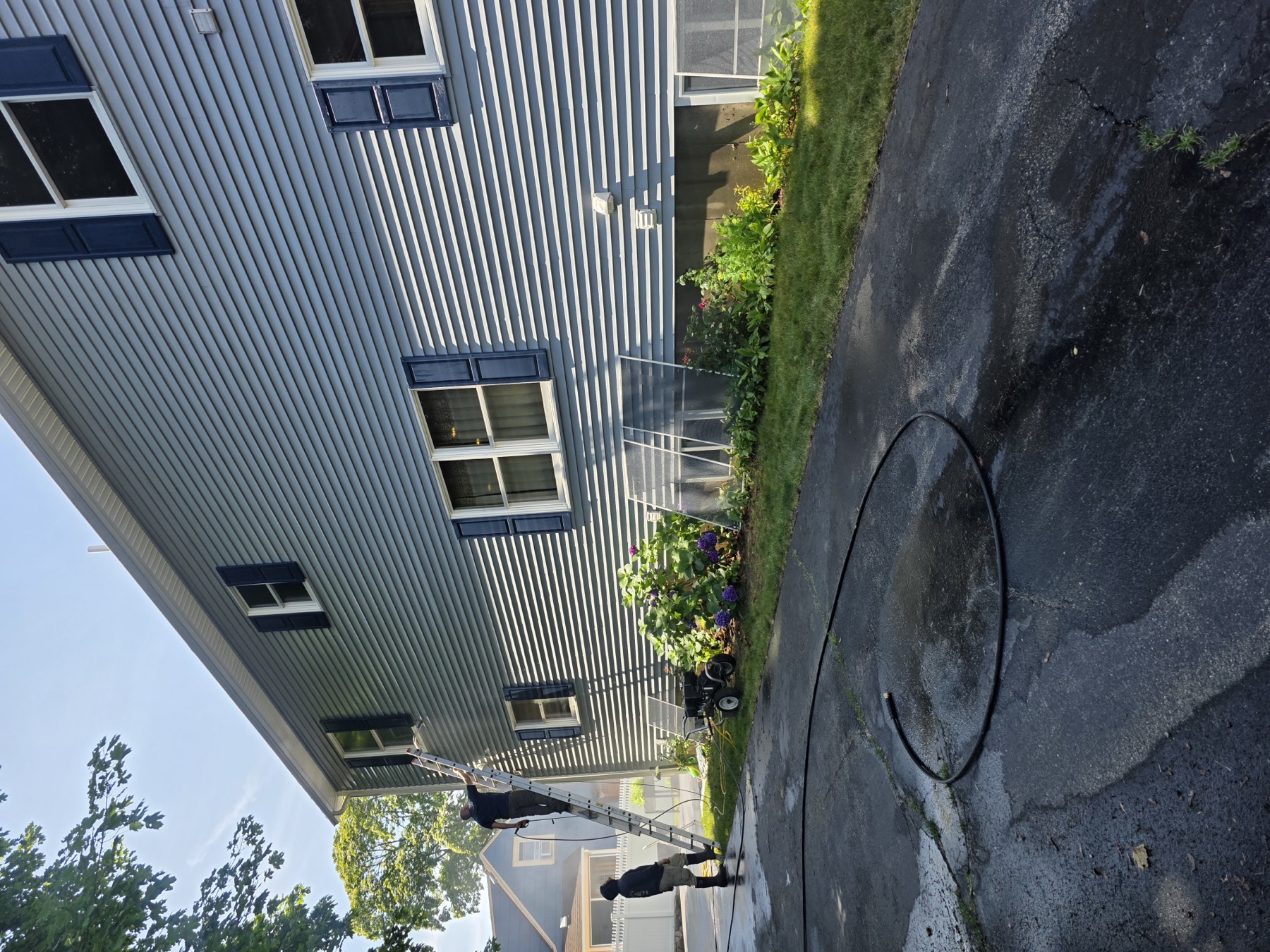 Crew pressure washing siding before painting